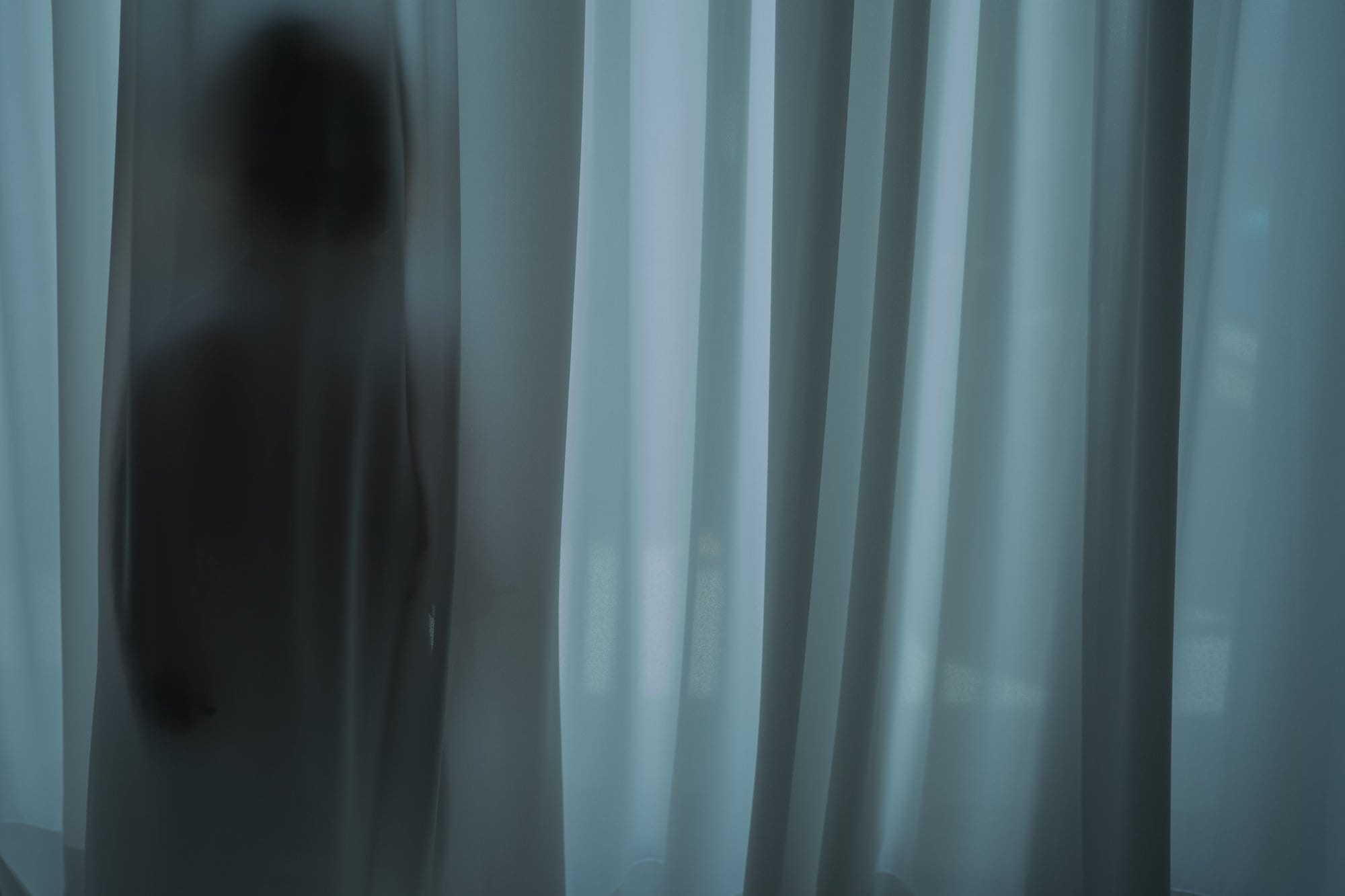 A figure's silhouette behind a curtain.