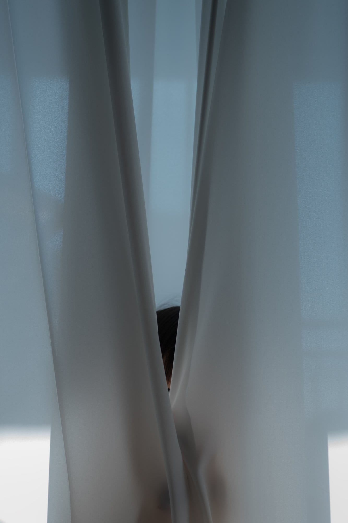 Part of a figure visible through a gap in the curtain.