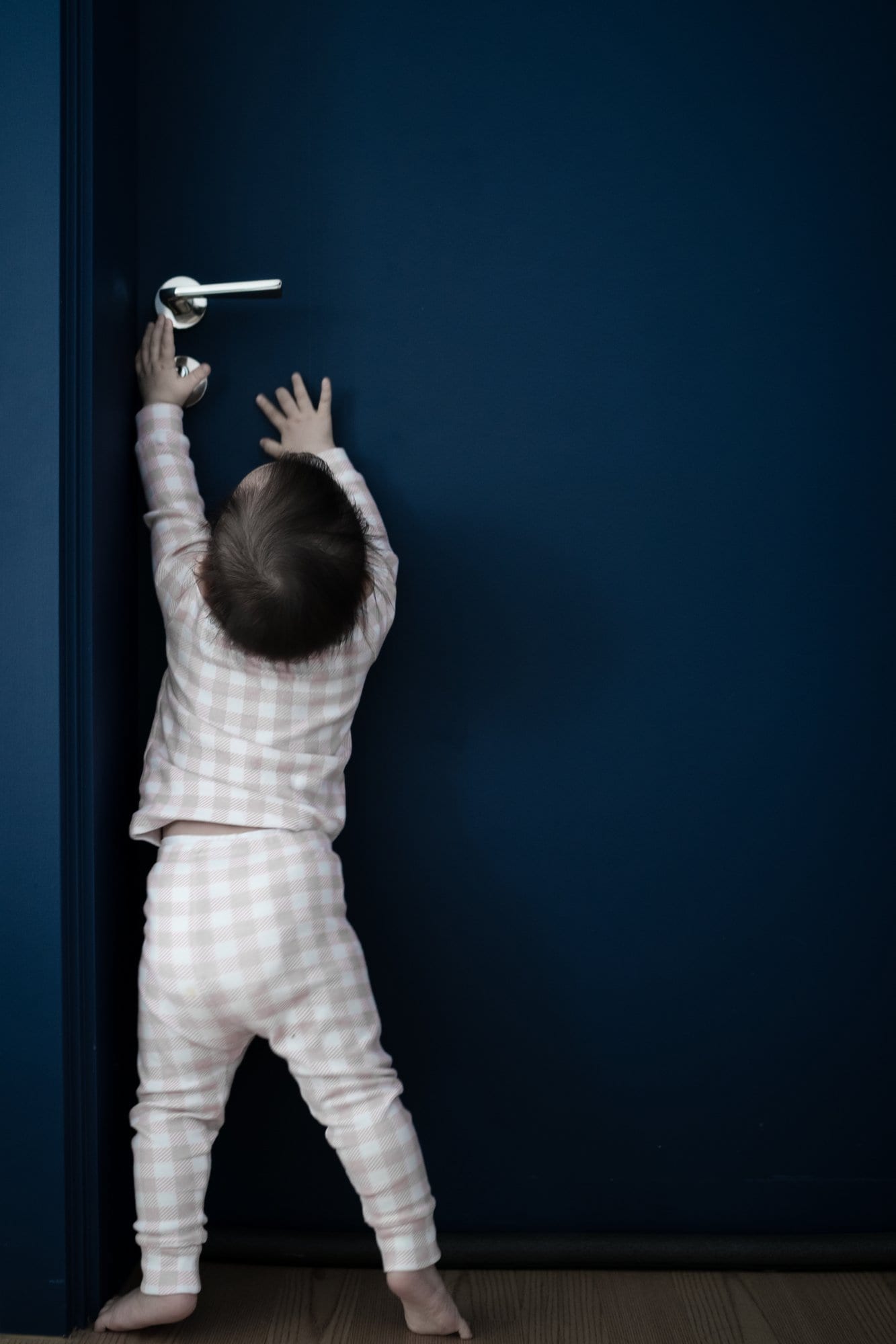 A child reaching with both hands toward a blue door.