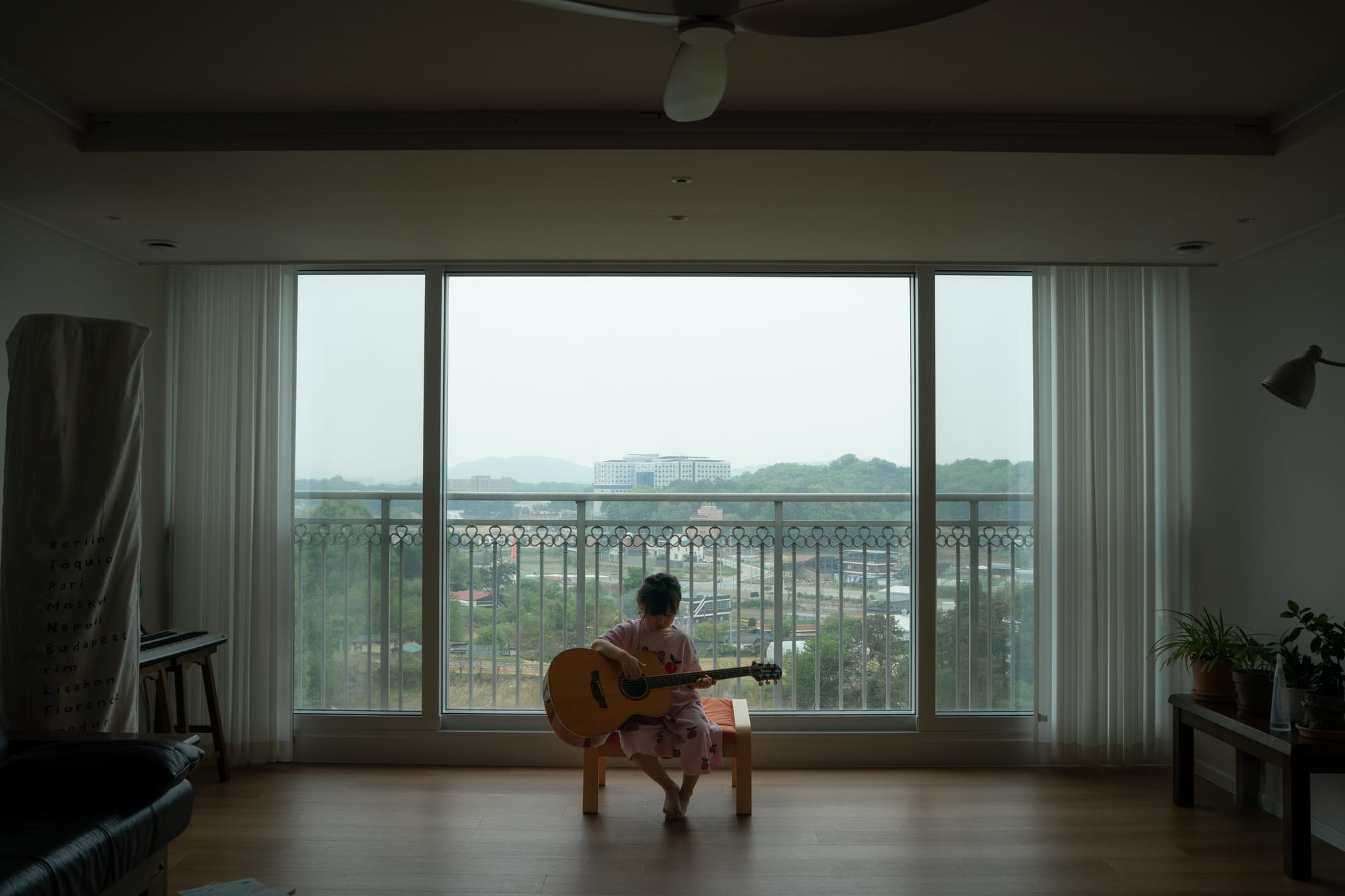 A child holds a guitar in the room.