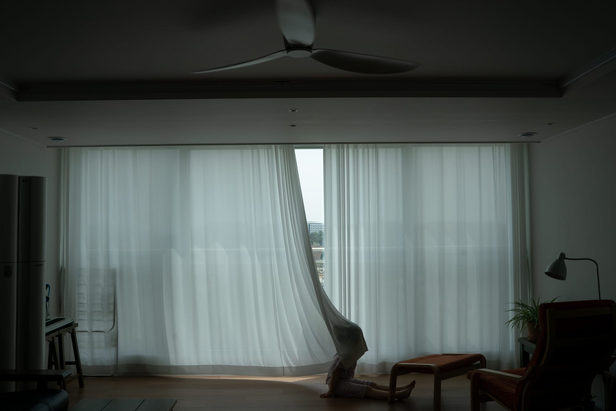 A child is partly hidden behind a curtain.