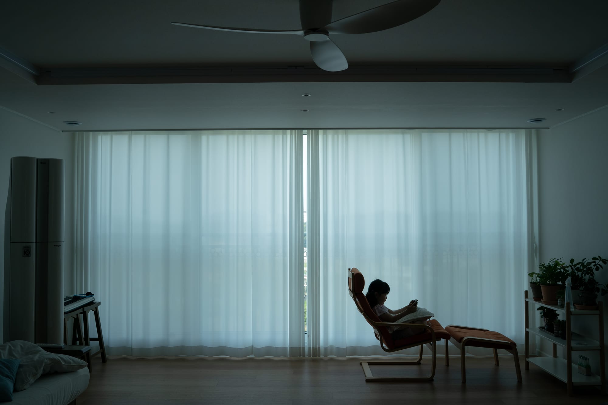 A child sits in a chair by the window.
