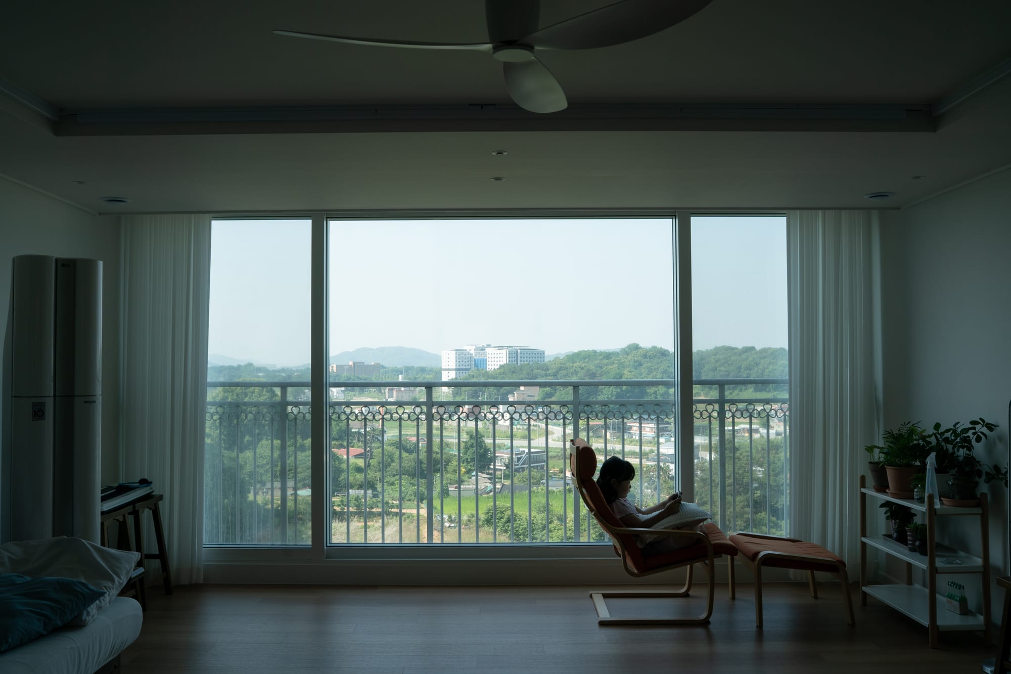 A child sits in a chair behind an open curtain.