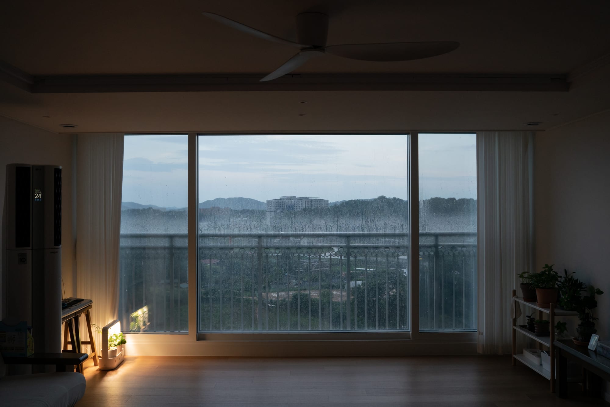 An empty room at dusk, with lights by the window.
