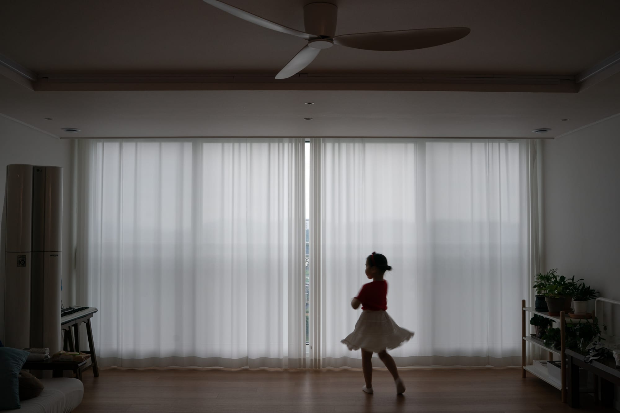 A child moves beside a white curtain.