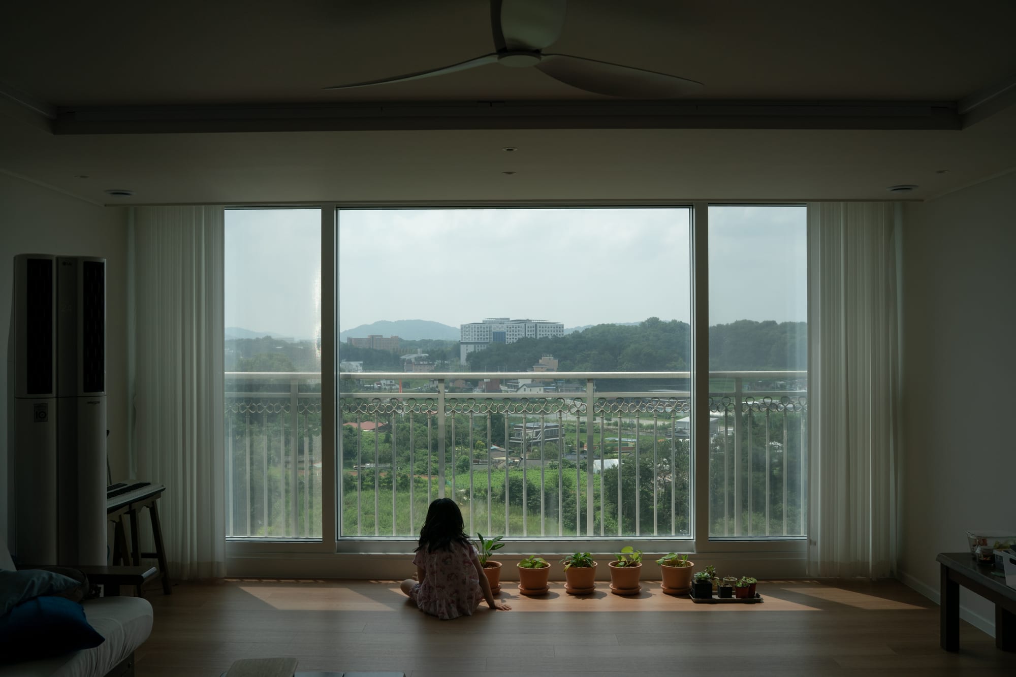 A child sits among potted plants.